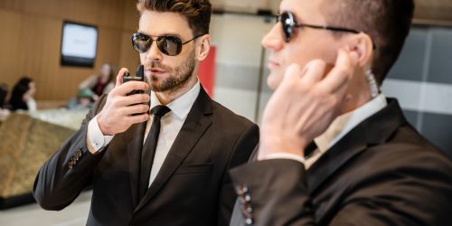 bodyguard service, private security, handsome man in sunglasses and formal wear communicating Diplomado en seguridad en conciertos y festivales