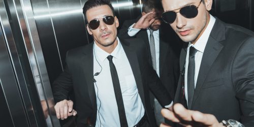 bodyguards stopping paparazzi and celebrity covering face with hand in elevator Diplomado en relaciones públicas para eventos de celebridades