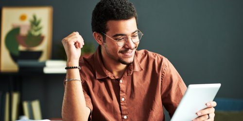 Young smiling student of online course of study looking at tablet screen Diplomado en analĆtica de datos y ROI en estrategias de marketing de evento